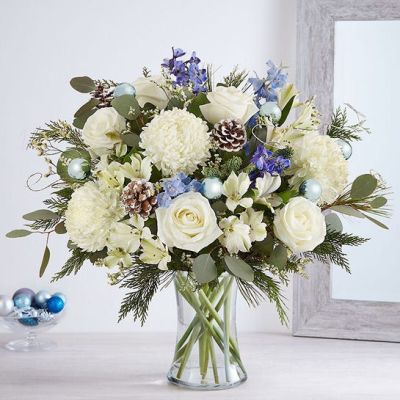 <p>Send wonderful winters wishes with our luxurious arrangement. Snowy white blooms are gathered with lush greenery, accents of blue, gray and glistening silver & gold. Loosely gathered in a glass vase, it’s a gift designed with stunning seasonal style.</p>