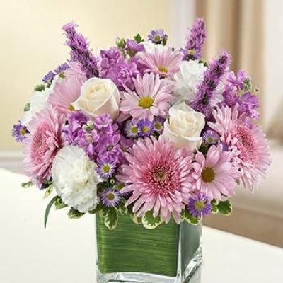 <p>This bouquet features a lavender and white arrangement of roses, stock, liatris, cremones, carnations, daisy poms and monte casino, accented with variegated pittosporum<br />
artistically designed by our florists in a classic clear glass cube vase lined with a Ti leaf ribbon.</p>